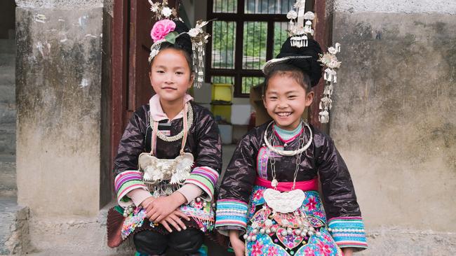 School girls sit in front of the entrance to their school classroom in the village of Huang Gang in Guizhou.