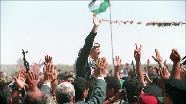 Yasser Arafat, chairman of Palestine Liberation Organisation, waving to a crowd of cheering Palestinians as he enters the newly self-ruled Gaza Strip for the first time in 27 years, in July 1994.