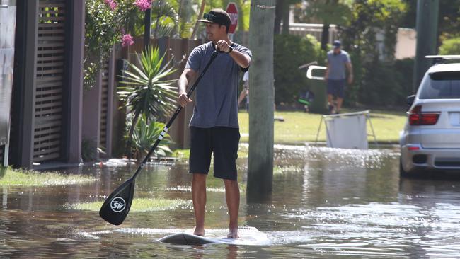 A man paddleboards through floodwater at Budds Beach on the Gold Coast on Tuesday morning. Picture: Glenn Hampson.