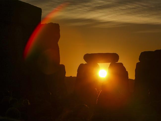 Revellers watch the sunrise as they celebrate the pagan festival of Summer Solstice at Stonehenge in Wiltshire, southern England on June 21, 2018. The festival, which dates back thousands of years, celebrates the longest day of the year when the sun is at its maximum elevation. Modern druids and people gather at the landmark Stonehenge every year to see the sun rise on the first morning of summer. / AFP PHOTO / Geoff CADDICK