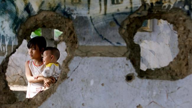 A Vietnamese girl holds her baby sister in the Quang Tri war museum, one of only a few structures that still bears witness to the Vietnam War. Picture: David Longstreath/AP