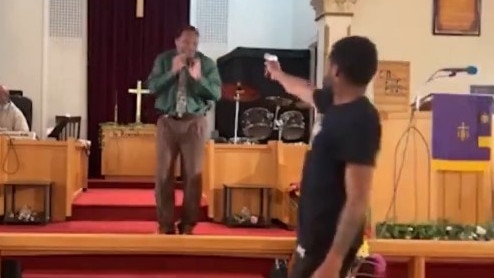 A man walks to the front of the church and aims a gun at the pastor. Picture: screengra - watch the vision above.