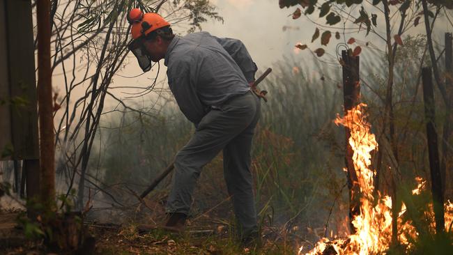 Homeowner Rod Meggs puts out spot fires in Kulnura. Picture: Dan Himbrechts