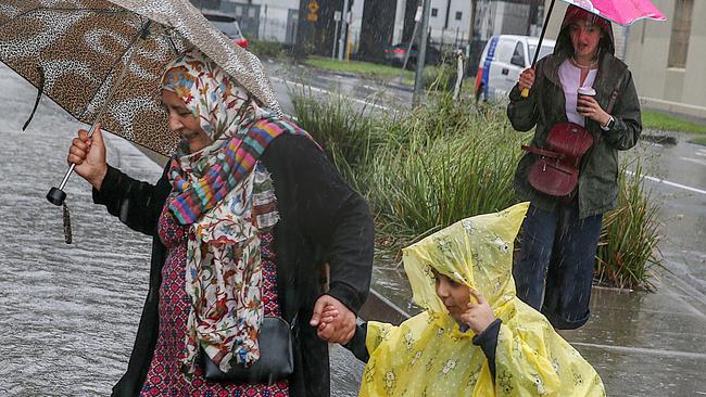 Pedestrians doing their best to stay dry in South Melbourne. Picture: Ian Currie