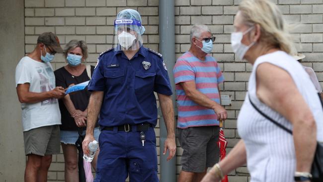 A paramedic wearing a protective face mask and shield assists people waiting in line at a coronavirus disease (COVID-19) testing clinic at Mona Vale Hospital in the wake of a new outbreak in the Northern Beaches area of Sydney, Australia, December 18, 2020. REUTERS/Loren Elliott