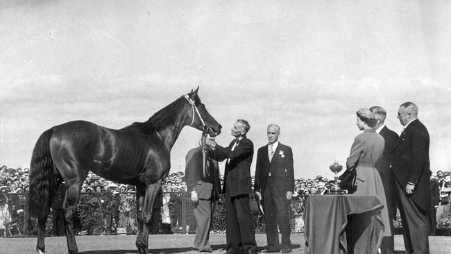 Queen Elizabeth II chats with EA Underwood and Sir Chester Manifold as their horse Cromis parades at Flemington in 1954.