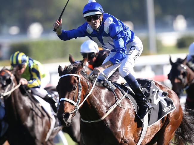 Hugh Bowman raises his whip to the crowd as Winx wins the 150th Epsom in 2015.