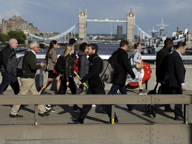 Commuters walk across London Bridge, with new security barriers in place. Picture: AP