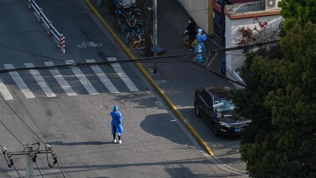 A worker wearing personal protective equipment stands on a near-deserted street in Shanghai/ Picture: Hector Retamal/AFP