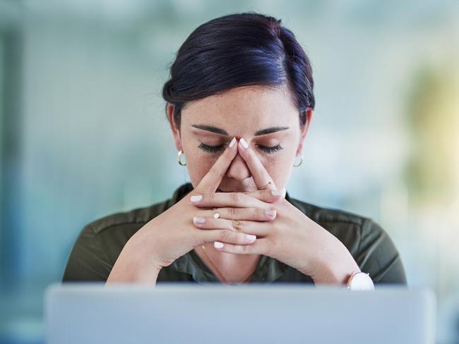 Shot of a young businesswoman looking stressed out while working in an office