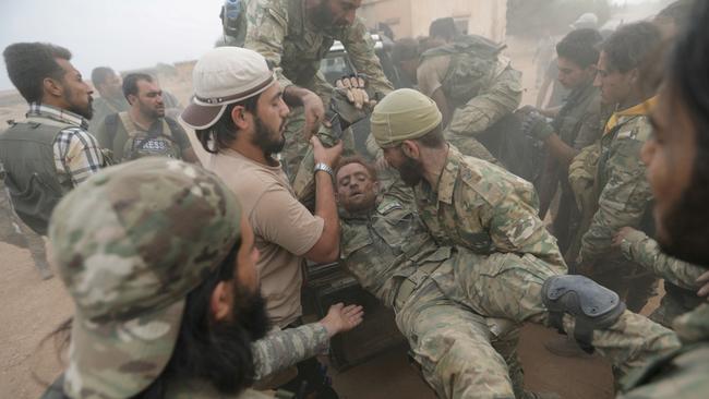 Turkey-backed Syrian rebel fighters assist a wounded comrade near the border town of Tal Abyad on Thursday. Picture: Reuters