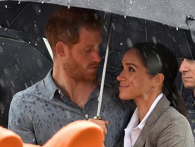 TOPSHOT - Britain's Prince Harry and his wife Meghan, Duchess of Sussex watch aboriginal dances at Victoria Park in Dubbo on October 17, 2018. - Prince Harry and his expectant wife Meghan visited a drought-stricken region of Australia on October 17, bringing a rare and welcome rainstorm with them. (Photo by Peter PARKS / POOL / AFP)