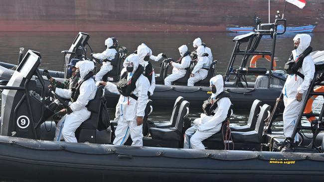 Elite Indonesian navy frogmen wearing protective gear keep watch on their boats as more than 300 Indonesian crewmembers of the Explorer Dream cruise ship are brought ashore at Jakarta for testing and quarantine. Picture: AFP