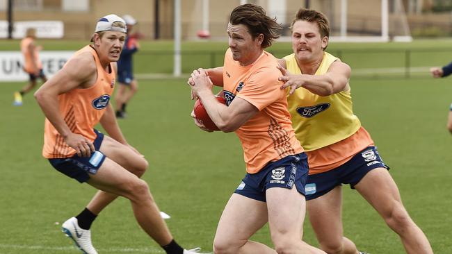 Recruit Tom Atkins tackles Patrick Dangerfield at Geelong training.