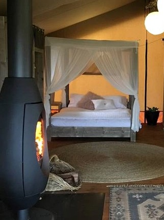 The four-poster bed and fireplace. Picture: Supplied/Glampinghub.com