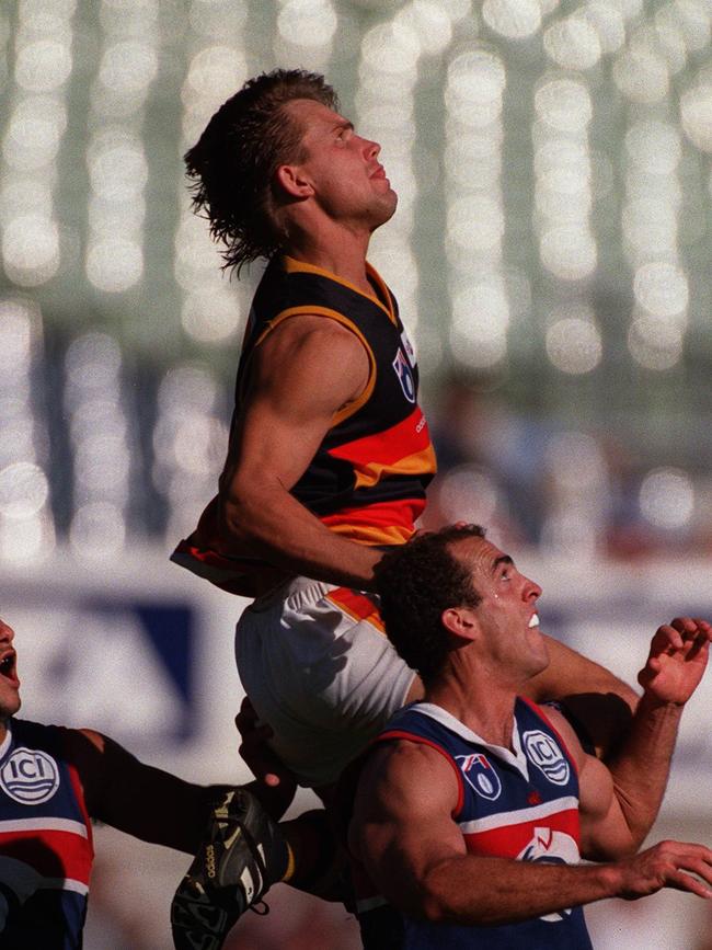 Tony Modra flies over Sedat Sir (left) and Matthew Croft at Optus Oval during his playing days.