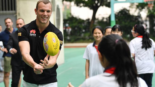 Australian swimmer Kyle Chalmers is seen passing an AFL football with children during a visit to a primary school in Shanghai, China.