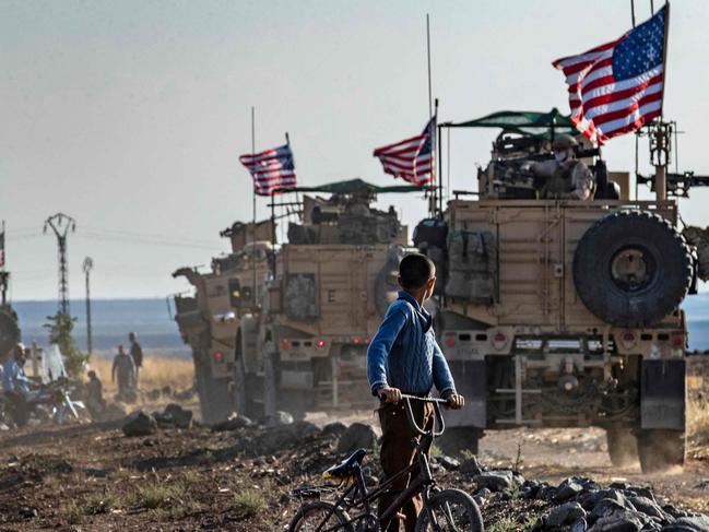 - AFP PICTURES OF THE YEAR 2019 -   A Syrian boy on his bicycle looks at a convoy of US armoured vehicles patrolling fields near the northeastern town of Qahtaniyah at the border with Turkey, on October 31, 2019. - US forces accompanied by Kurdish fighters of the Syrian Democratic Forces (SDF) patrolled part of Syria's border with Turkey, in the first such move since Washington withdrew troops from the area earlier this month, an AFP correspondent reported. (Photo by Delil SOULEIMAN / AFP)