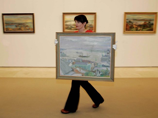 <p>Lauretta Morton hangs one of artist Margaret Olley's paintings of Newcastle at the Newcastle Regional Art Gallery. Picture: Chris Hyde</p>