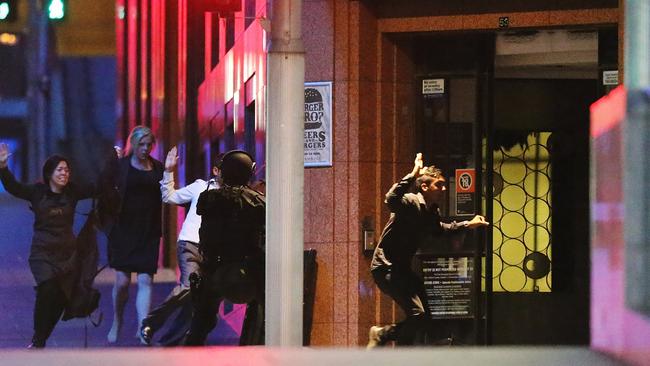 Hostages run with their hands up from the Lindt cafe. Picture: Joosep Martinson/Getty Images