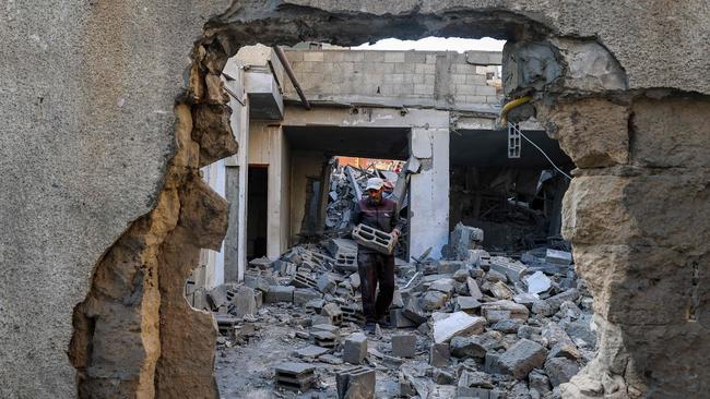 TOPSHOT - A man carries salvaged concrete blocks inside a building hit in an Israeli strike in the Bureij camp for Palestinian refugees in the central Gaza Strip on May 2, 2025. (Photo by Eyad BABA / AFP)