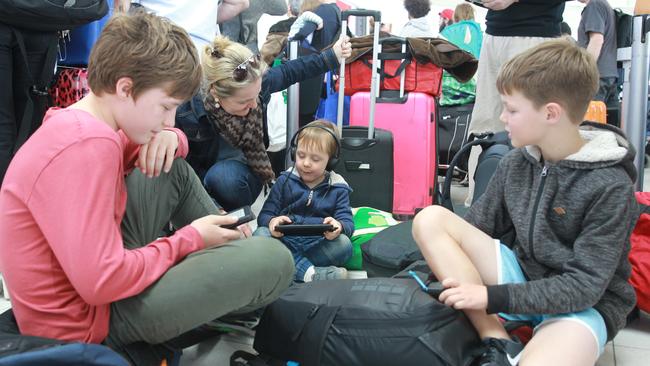 This could take a while: Penny Stewart from Brisbane and her three boys, James, 14, Owen, 4, and Xavier, 10, wait it out in Adelaide. Picture: AAP/Dean Martin