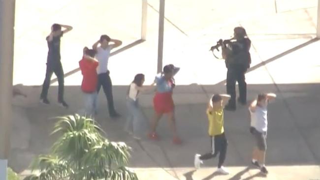 Students raise their hands as they’re evacuated from the school. Picture: CBS