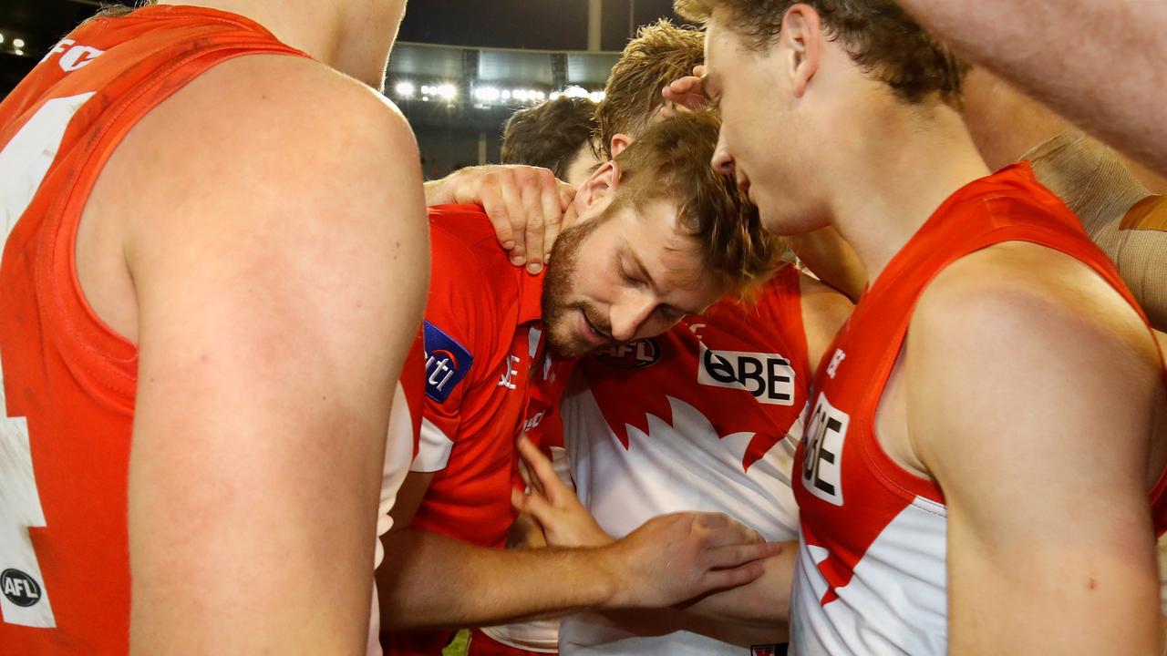 An injured Alex Johnson is consoled by his Sydney teammates on Sunday night.
