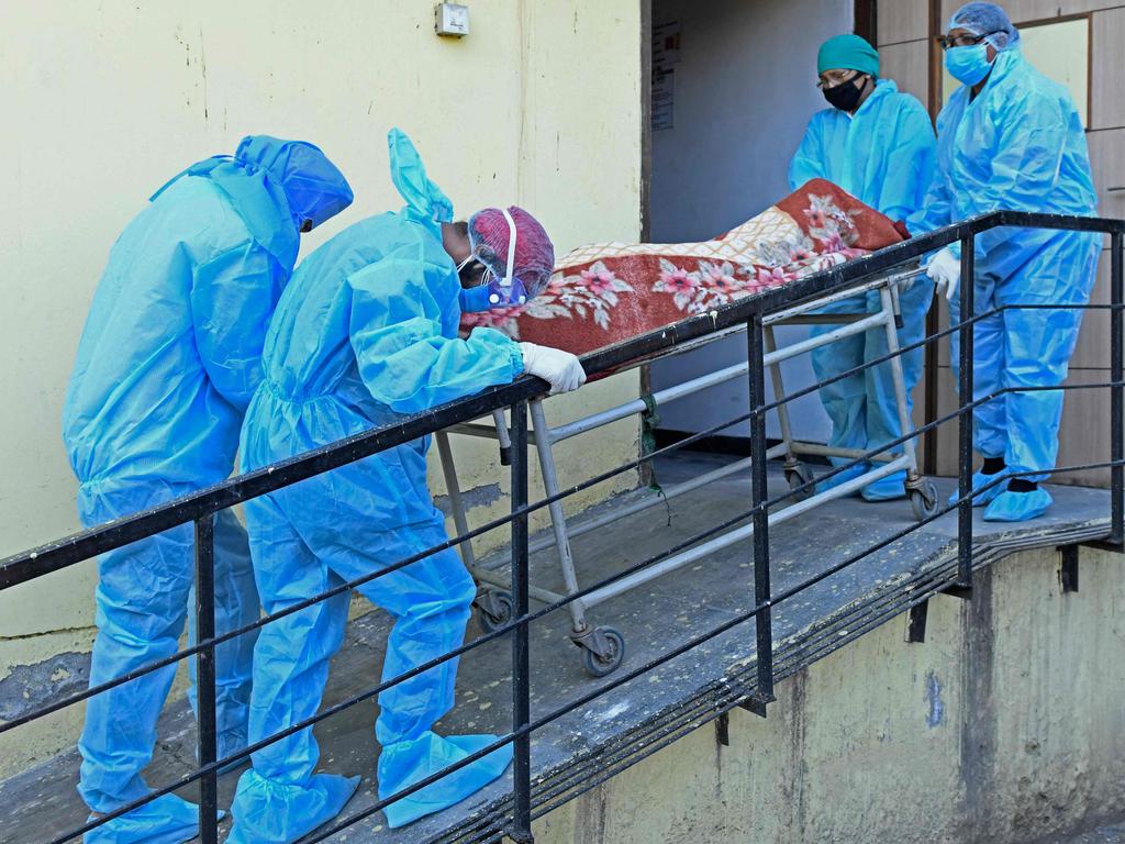 Members of medical staff wearing protective gear carry the dead body of a COVID-19 coronavirus victim at a hospital in Amritsar.