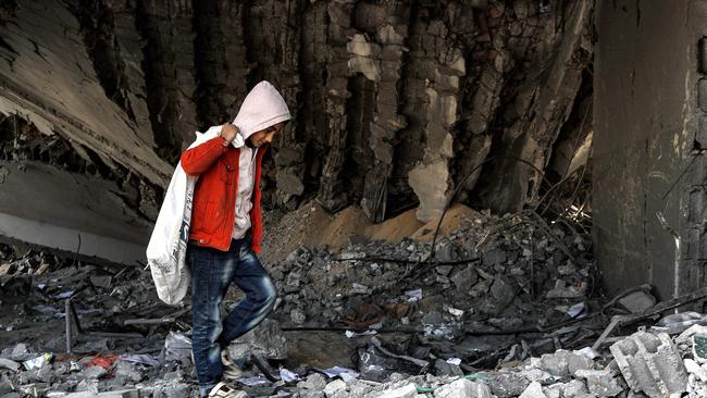 A boy walks with a sack while searching for debris to be salvaged from the rubble of a destroyed high school in the Nuseirat camp for Palestinian refugees, which was severely damaged by Israeli bombardment. Picture: Photo by ANAS BABA / AFP