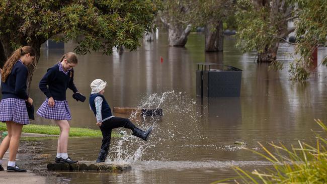 Bystanders watch the flooding along the shores of the Port of Sale in Gippsland. Picture: Jason Edwards