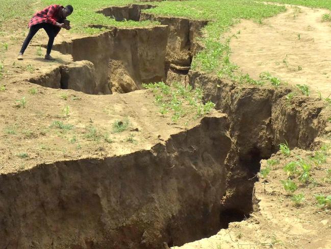 In this photograph taken on April 6, 2018, a man takes photograph of a deep chasm in the earth - which has appeared following heavy downpours of rain in March - near the town of Mai-Mahiu, Nakuru County in the Rift Valley, some 54kms (33.5 miles) south-west of Nairobi. / AFP PHOTO / SIMON MAINA