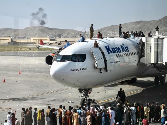 Afghan people climb atop a plane as they wait at the airport in Kabul on August 16, 2021. after a swift end to Afghanistan's 20-year war, as thousands of people mobbed the city's airport trying to flee the Taliban’s takeover. Picture: Wakil Kohsar/AFP