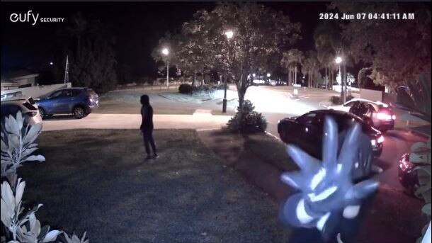 A masked youth reaches to pull down a security camera before a BMW was stolen in Helensvale on Friday morning. Picture: Supplied.