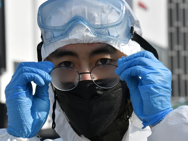 A South Korean soldier adjusts his glasses as he sprays disinfectant on the street to help prevent the spread of the COVID-19 coronavirus, in Seoul on March 6, 2020. - South Korea's total reported infections -- the largest figure outside China, where the coronavirus first emerged -- rose to 6,284 on March 6, the Korea Centers for Disease Control and Prevention said. (Photo by Jung Yeon-je / AFP)