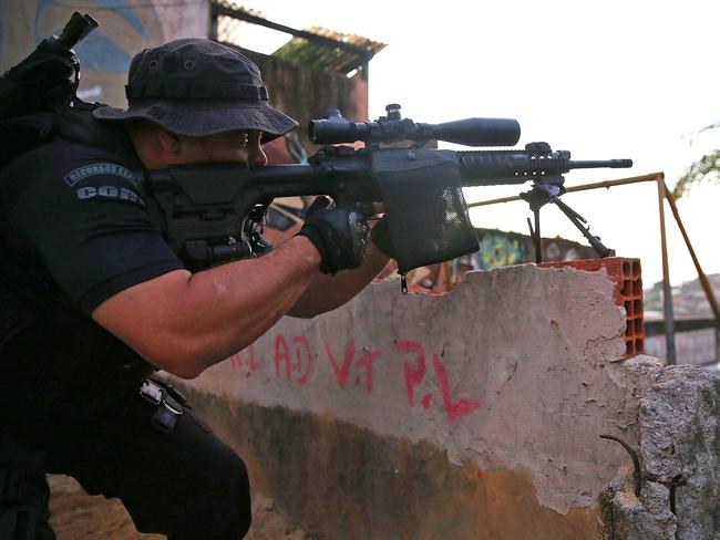 An officer from the CORE police special forces aims his weapon during an operation to search for fugitives in the Complexo do Alemao “favela” in Rio de Janeiro.