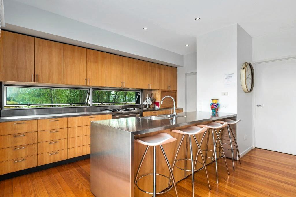 The kitchen features a stainless steel bench top contrasted against timber-grain cupboards. It is part of an open-plan living area also incorporating the lounge room and dining room. Picture: Alicia Harvey Real Property