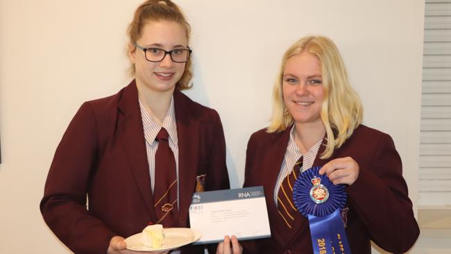 2018 Sandgate District State High School students Kate Estreich and Liliana Tognolini with the winning camembert in the Royal Queensland Show’s Student Made Cheese Competition.