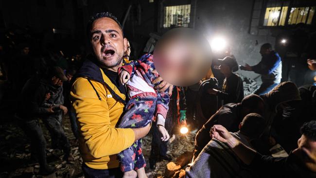 A man reacts as he holds a young victim removed from under the rubble of a building hit by an Israeli strike on Rafah. Picture: Mahmud HamsAFP