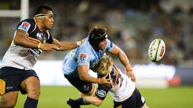 Damien Fitzpatrick of the Waratahs offloads in the tackle of Matt Lucas of the Brumbies (right).