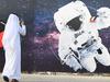 (FILES) In this file photo taken on September 25, 2019 (FILES) In this file photo taken on September 25, 2019 a man takes a picture of an illustration depicting an astronaut with the Emirati national flag outside Mohammed Bin Rashid Space Centre (MBRSC) in Dubai. - The first Arab space mission to Mars, set for launch next month to study the Red Planet's atmosphere, is designed to inspire the region's youth and pave the way for scientific breakthroughs, officials said on June 9, 2020. (Photo by KARIM  SAHIB / AFP)