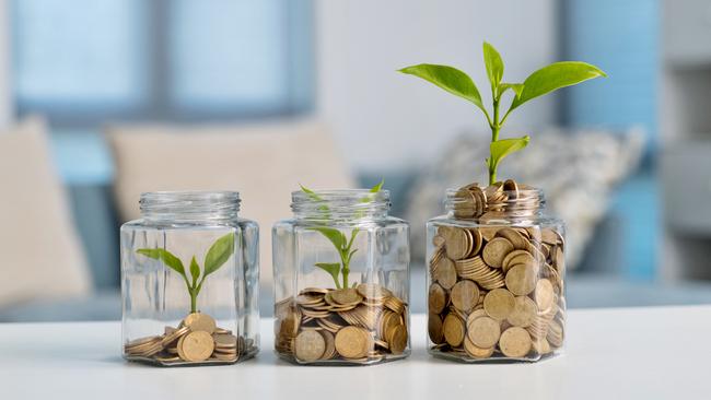 Green plant growing in glass jar with coins, superannuation generic