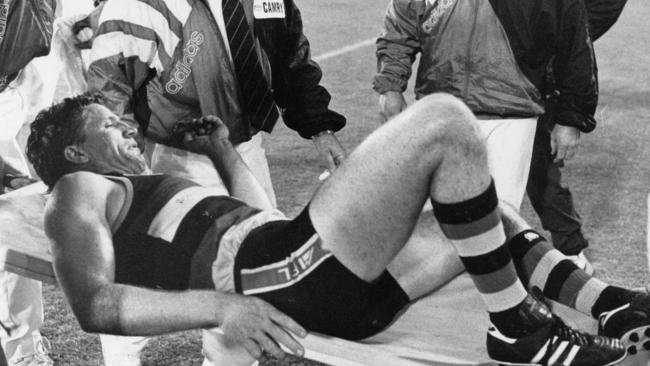 McDermott being taken off ground on stretcher after clash with Hawthorn player Dermott Brereton in 1991.