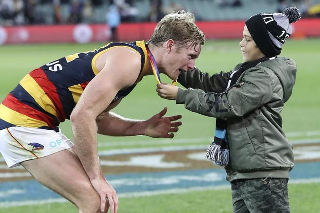 Crows defender ALex Keath awarded the Showdown 46 medal from a young Power supporter at Adelaide Oval. Picture Sarah Reed