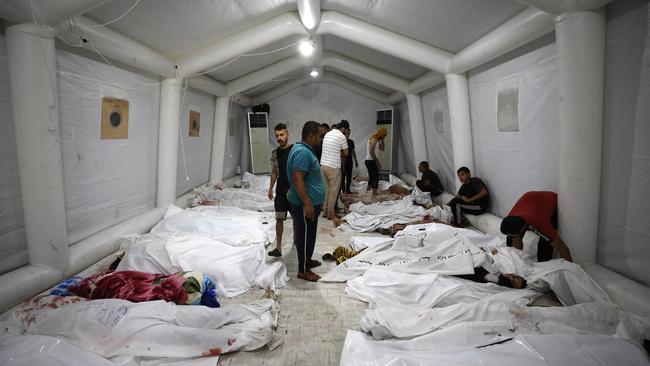 People stand over bodies of Palestinians killed in a strike on the Ahli Arab hospital in central Gaza.