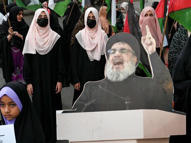 Shiite Muslims carrying Palestinian national flags stand beside a portrait of slain Lebanese Hezbollah chief Hassan Nasrallah, during an anti-Israel protest in Lahore on September 28, 2024. Hezbollah chief Hassan Nasrallah has been killed, the Lebanese movement said on September 28, dealing a seismic blow to the Iran-backed group that has been engaged in a year of cross-border hostilities with Israel. (Photo by Arif ALI / AFP)