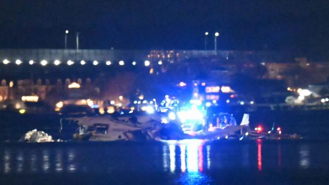 Part of the wreckage is seen as rescue boats search the waters of the Potomac River after a plane on approach to Reagan National Airport crashed into the river outside Washington, DC.