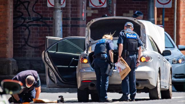 Police with evidence bags check a Silver Mazda sedan on Flinders St. Picture: Jason Edwards