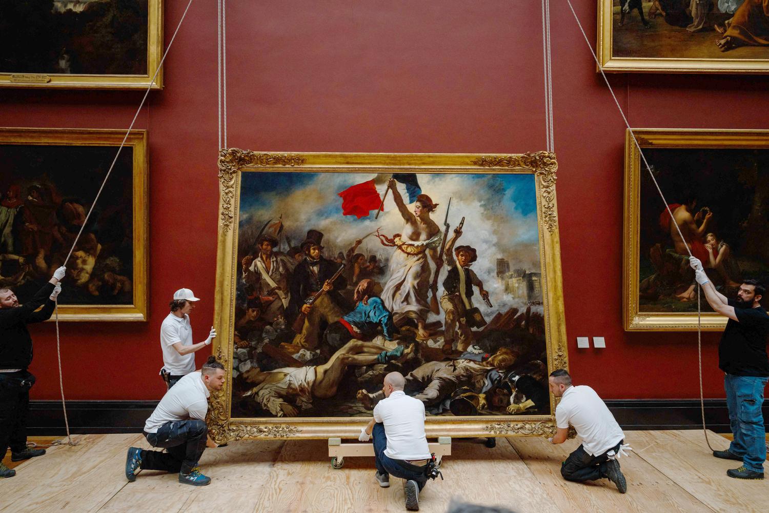 Employees of the Louvre Museum hang the painting "Liberty Leading the People" (1830) by French artist Eugene Delacroix. Picture: Dimitar Dilkoff/AFP