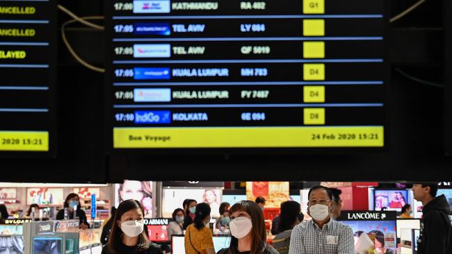 Passengers with protective masks look at a flights information board at Suvarnabhumi airport in Bangkok. Picture: Hector Retamal/AFP